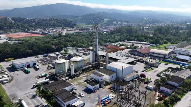vis&atilde;o a&eacute;rea vertical de uma ind&uacute;stria de gases industriais, com tanques, tubula&ccedil;&otilde;es e estruturas met&aacute;licas, capturada em dia claro e ensolarado por drone