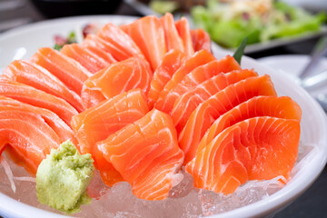 Raw salmon slice or salmon sashimi and wasabi in Japanese style fresh serve on ice in white bowl. Japanese traditional food or with low calories and high nutrition and healthy diet dish.