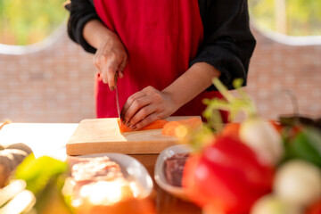 A woman is cutting a carrot on a cutting board