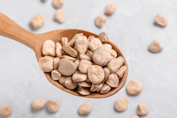 Raw dry Grass pea close up on wooden spoon. Healthy, protein source for vegan and vegetarian diet. Traditional Italian apulian cuisine ingredient. Legumes known as Cicerchia, Vetch, Indian Pea
