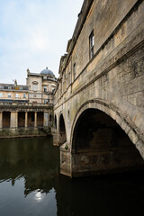 Obraz premium Pulteney bridge of Bath in Somerset - Cotswolds. Famous limestone bridge with church buildings in the background