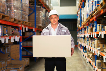 A warehouse worker is carrying a box, showcasing diligence and teamwork in a productive environment.