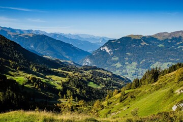 Fototapeta premium Mountain valley with trees and clear blue sky in daylight scene