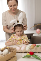 A delightful and joyful moment shared between a mother and her daughter as they decorate colorful Easter eggs at home