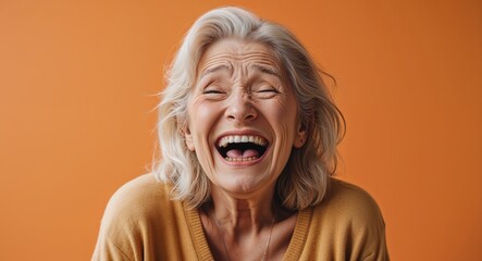 blonde elderly woman on orange plain bright background happy laughing hysterical looking at camera portrait banner with copy space ad concept marketing
