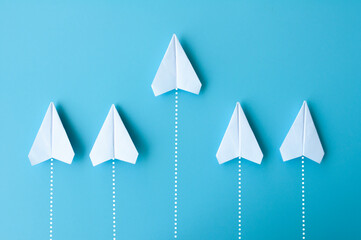 Top view of white paper airplanes origami flying on blue background
