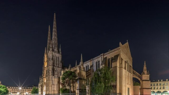 Cathedrale Saint-Andre de Bordeaux night timelapse hyperlapse with twin spires. Illuminated buildings and trees on the Pl. Pey Berland square create an evening urban atmosphere. Bordeaux, France