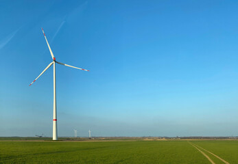 windmill in green field with distant opencast mining excavator concept for energy supply and...