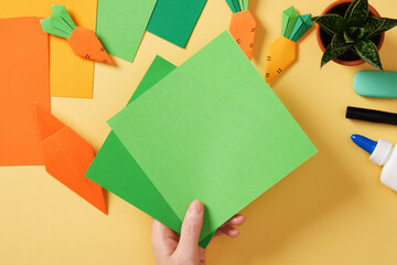 Making a simple origami carrot Easter craft. Take green colored paper to make the haulm. Around the...
