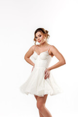 Naklejka premium Elegant young woman in a white dress posing gracefully against a plain backdrop in a studio setting