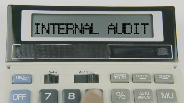 "Internal Audit" text or words displayed on a calculator's LED screen as a hand types numbers, symbolizing the process of examining and evaluating the organization's financial systems and controls