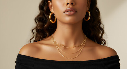 Woman wearing chunky gold hoop earrings and a layered gold chain necklace, set against a soft, neutral background with warm lighting that highlights the jewelry shine.