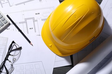 Different architectural drawings, hard hat, pencil and glasses on table, flat lay