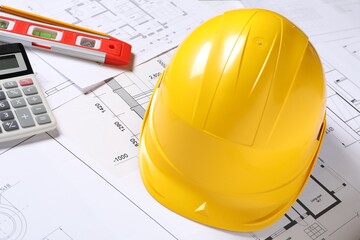 Hard hat, pencil, calculator and building level on different engineering drawings, closeup