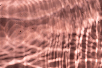 Mediterranean pink terracotta color plaster background with under water sun shadows. 