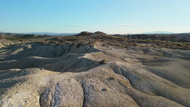 Golden hour rays casting warm light across barren badlands, revealing rugged geological formations of bardenas reales natural park in navarre, spain