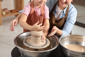 Hobby and craft. Smiling mother with her daughter making pottery indoors, closeup
