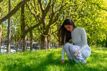 Gen Z woman picking up daisies flowers in a public park in Stuttgart city, Germany