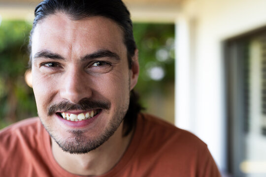 Smiling man with long hair enjoying time in garden, looking cheerful and relaxed, copy space