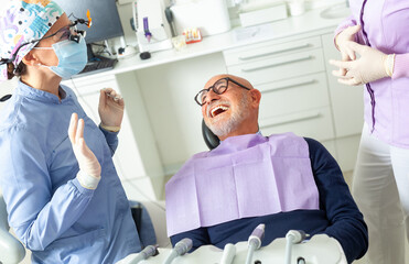 Senior man laughing during dental checkup with dentist and nurse