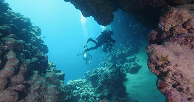 Silhouette of a scuba divers swimming in an underwater cave. A divers explores underwater cave ecosystems. Scuba diving training and education.