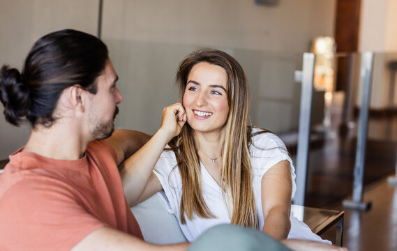 Smiling friends relaxing on sofa at home, enjoying conversation together