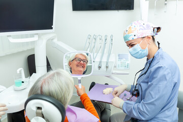 Fototapeta premium Senior woman looking at her new smile in dental clinic