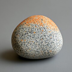 A smooth rounded rock displays a blend of colors and textures