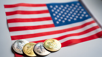 Gold and silver Bitcoin coins lying on the American flag. Conceptual photo representing...