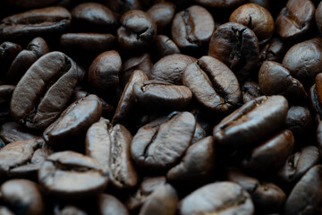 Macro close-up of roasted coffee beans showing detailed texture, rich dark color, and natural shine, ideal for backgrounds related to coffee, cafés, and gourmet beverages.