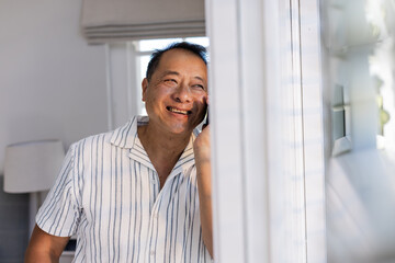 Smiling Senior Asian man talking on smartphone at home, enjoying conversation