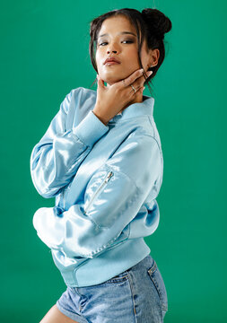 Confident Asian woman posing in blue jacket and denim shorts, striking pose