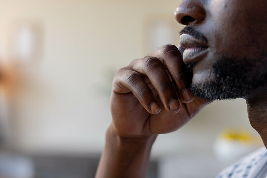 Thoughtful man resting chin on hand, contemplating indoors in casual setting