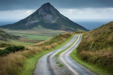 A winding country road leads towards a large mountain landscape