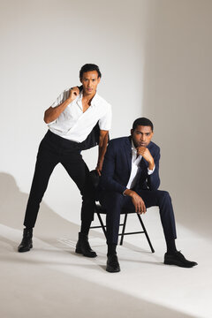 Confident men in stylish suits posing in modern fashion studio setting