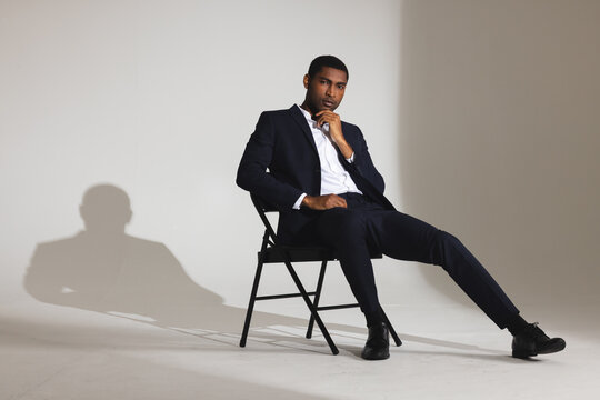 Confident man in stylish suit sitting on chair in modern studio