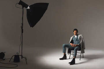 Confident man in stylish suit sitting under studio lights, exuding elegance