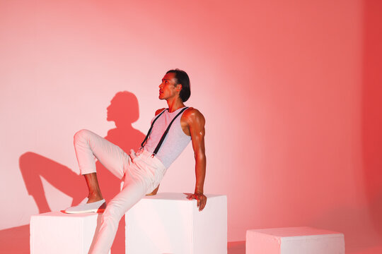 Fashion model in stylish outfit posing confidently on white cubes in studio