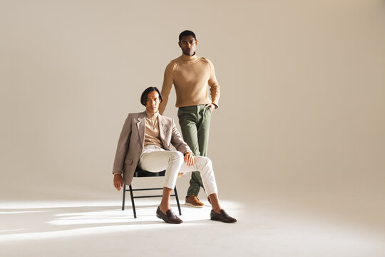 Stylish men in modern outfits posing confidently in bright fashion studio