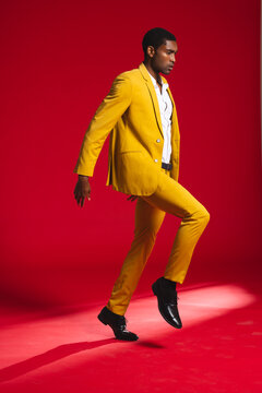 Confident man in vibrant yellow suit posing dynamically in modern studio