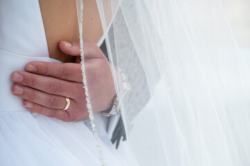 Groom’s hand on bride’s waist under delicate wedding veil