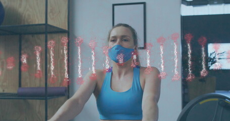 Dna structure spinning against caucasian woman wearing face mask performing rowing exercise at gym