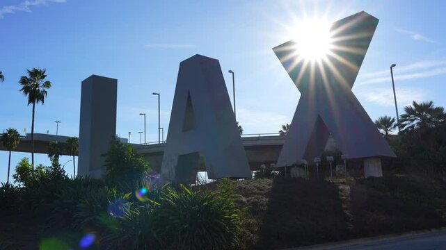 Los Angeles, California - January 6, 2025: Large blue LAX sign set against a backdrop of a clear blue sky and lush greenery.