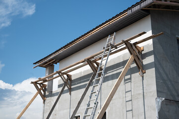 Wooden scaffolding with metal ladder is being built on a house facade during renovation under blue...