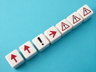 Obraz premium A line of white cubes with upward arrows is interrupted by a single red cube displaying exclamation marks