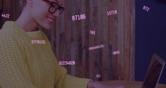 Multiple changing numbers floating against caucasian woman smiling while using laptop