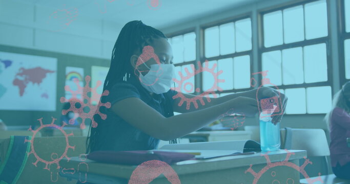 Image of covid 19 icons over schoolgirl in face mask using hand sanitizer