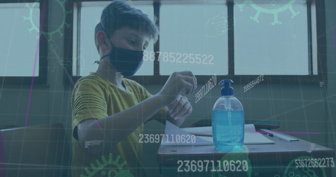 Image of covid 19 icons and numbers changing over schoolboy in face mask using hand sanitizer
