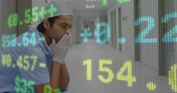 Stock market data processing against stressed male surgeon sitting in the corridor at hospital