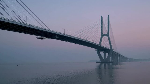 A Serene Early Morning Scene of a Modern Bridge Over a Calm River with Mist and Soft Light